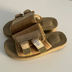 Beige sandaler från Suicoke i mocka - Säljer ett par beige sandaler från Suicoke med breda remmar i mocka och textil, justerbara spännen och Vibram-sula. Snygg chunky look.