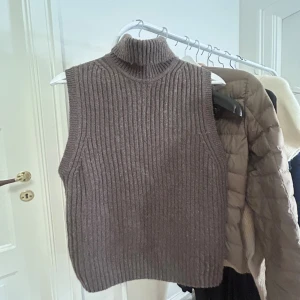 Ribbad brun stickad väst & Other Stories - Ribbstickad brun väst från & Other Stories med hög krage. Perfekt nu till hösten. Säljs inte längre 