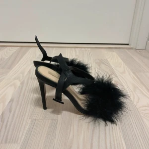 Svarta klackar med fjädrar - Säljer ett par svarta pumps med hög klack och fluffiga fjädrar framtill. Inte används alls och är i storlek 38.