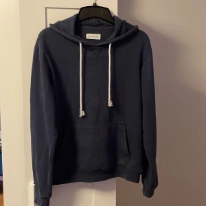 Mörkblå hoodie från Pier One - Tja säljer nu en mörkblå hoodie från Pier One med vit snörning. Tröjan har huva och långa ärmar, perfekt för kyliga dagar. Enkel och stilren design som funkar till det mesta.