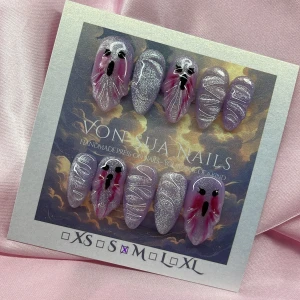 LilacScreams(M); Medium Almond - Handgjorda press-on naglar i storlek M från Von Sua Nails. Naglarna är lila med glittereffekt och har detaljer i vitt och rosa samt svarta spökansikten. Mix av spetsig och rundad form, perfekt för dig som vill sticka ut med en unik och kreativ look.