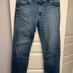 Blå jeans från Lee straight fit - Säljer ett par klassiska blå jeans från Lee med rak passform. Jeansen har fem fickor, normal midja och snygga slitningar för en avslappnad look. Tillverkade i tåligt denimtyg som passar perfekt till sneakers. Nypris: 599kr. Storlek: W31 L32
