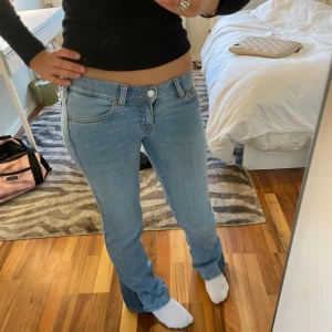 Ljusblå bootcut jeans  - Säljer ett par ljusblå jeans från Wrangler. Jeansen är utsydda där nere.