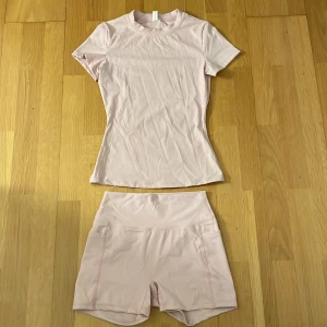 Ljusrosa träning set - Säljer en ljusrosa, tight och kortärmad träningstopp som är mjukt och stretchigt tillsammans med ett par matchande shorts. Shortsen har även två fickor för telefonen vid sidorna. Perfekt för gym eller löpning. Står S men skulle rekommendera någon som är xs. Vid frågor och bild skriv gärna🩷