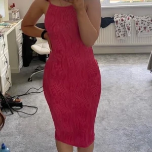 Rosa  klänning  - Säljer en snygg rosa klänning med smala axelband som går att justera och ribbat vågmönster. Klänningen har en slits baktill. De är mycket stretch i den är S men passar upp till L