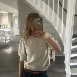 Vit stickad tröja med puffärm - Superfin vit stickad tröja med korta puffärmar och rund hals. Tröjan har ribbade muddar vid ärmslut och nederkant, vilket ger en snygg passform. Perfekt för lager-på-lager och funkar året runt.