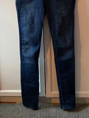 Mörkblå repley model luz - Snygga mörkblå skinny jeans med klassisk femficksdesign och smal passform. Jeansen har en enkel look utan slitningar eller dekorationer, perfekta till vardagsstilen. Tillverkade i mjuk bomullsblandning för skön känsla.