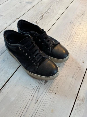 Svarta sneakers från Lanvin - Stilrena svarta sneakers från Lanvin. Skorna är storlek 42 men passar lite större. Hör av er vid fler frågor! Priset är inte hugget i sten!