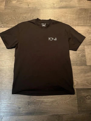 Polar Skate - Säljer en svart t-shirt från Polar Skate Co med liten vit logga på bröstet och stor grafisk print på ryggen. Klassisk passform och korta ärmar, perfekt för en clean streetwear-look. Tillverkad i mjuk bomull för skön känsla hela dagen.