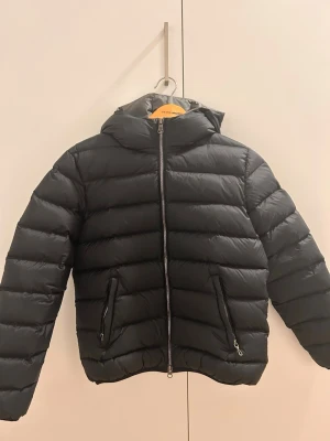 Svart dunjacka från Colmar - Snygg svart dunjacka från Colmar med huva och dragkedja framtill. Jackan har två fickor med dragkedja och klassisk pufferstil. Perfekt för kyliga dagar och enkel att matcha med olika outfits. Storlek XS använd cirka 3 gånger💓 hör av er om ni har frågor!