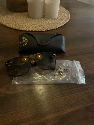 Rayban boyfriend  - Snygga Ray-Ban boyfriend solglasögon med brunmelerad båge och mörka glas. Klassisk fyrkantig form och logga på skalmen. Kommer med originalfodral och plastpåse. Tyvärr så har rayban på sidan lossnat men annars i top skick 