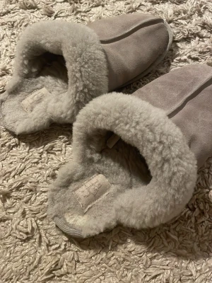 Beige fårskinnstofflor från UGG - UGG tofflor. Använd många gånger. Helen och på högra tofflan är det tecken på användning (syns på bilden)