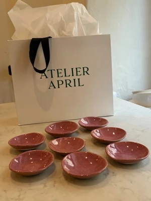 Rosa små fat från Atelier April - Säljer åtta små runda fat i handgjord keramik från Atelier April. Faten är glaserade i en varm rosa ton och har en blank yta. Perfekta för smycken, snacks eller som dekoration. Helt nya och tål maskindisk.