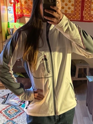 Sip up - Bekväm sip up tröja i vitt med grå och lila inslag. Två fickor vid magen och en ficka vid bröstet är alla funktionella. Insidan är mjuk och kragen sitter löst vid halsen. Köpt på second hand men endast använt en gång av mig, inga fläckar och i mycket bra skick 