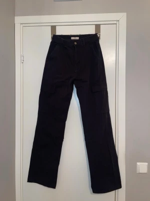 Svarta cargopants från STR, stl 40 - ✨Svarta cargopants TALL från STR med klassiska cargofickor på sidorna och raka ben. Byxorna har normal passform och är tillverkade i ett slitstarkt bomullsmaterial. Perfekta för en avslappnad och trendig look ✨