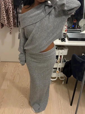 Stickat set  - Säljer ett grått stickat set med off shoulder-tröja och lång kjol med låg midja. Setet är i mjukt, stretchigt material och har en avslappnad passform. Står ingen storlek, men skulle säga att de är i S. 