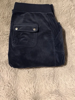 Mörkblåa mjukisbyxor i velour - Säljer ett par marinblå Juicy-byxor i storlek L. Inte synliga slitage, de är nersydda.