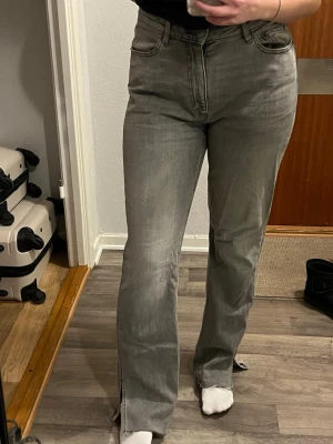Gråa bootcut jeans med slits - Gråa jeans med bootcut och slits i modellen ”split” från Lager 157. Hög midja. Som referens är jag 170cm lång och väger ca 72 kg. Som ni ser är de lite stora för mig så jag skulle säga att de passar någon som brukar bära L-XL i jeans. 