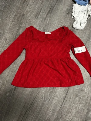 Röd blus med lång ärm från Nelly  - Röd blus från Nelly med mönster och volang. Helt ny aldrig använd.