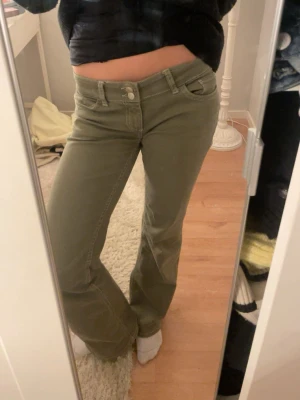 Olivgröna bootcut jeans - Snygga olivgröna jeans med bootcut-modell och vita kontrastsömmar. Jeansen har klassisk femficksdesign och normal passform. Perfekta för dig som vill ha en cool och avslappnad stil.