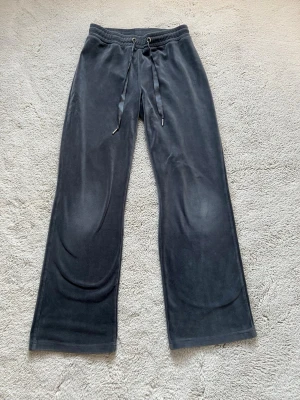 Mörkgrå mjukisbyxor från Gina Tricot - Säljer ett par mörkgrå mjukisbyxor från Gina Tricot i storlek S. Byxorna har breda ben, snörning i midjan och är gjorda i mjukt och skönt material. 