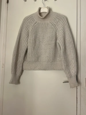 Beige stickad polotröja från H&M - Säljer en beige stickad polotröja från H&M i storlek M. Tröjan har grovstickad struktur, hög polokrage och långa ärmar med ribbade muddar. Perfekt för att hålla sig varm och snygg under kyliga dagar. Pris kan diskuteras, tvätt ingår innan leverans  