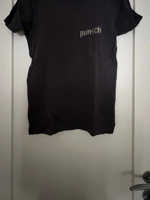 Grå t-shirt med punsch-tryck - Grå t-shirt med coolt tryck 'punsch' i vitt på bröstet. Klassisk rund hals och korta ärmar. Skön passform och tillverkad i mjuk bomull som känns nice mot huden. Perfekt till jeans eller shorts för en avslappnad look.