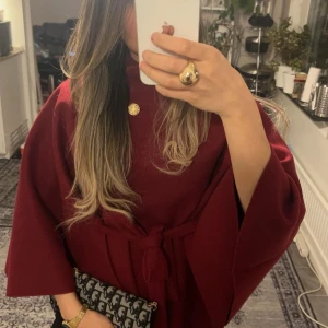 Vinröd poncho - Säljer en vinröd poncho. Har inte använt den så mycket.