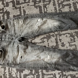 Grå slitna jeans från Jack & Jones - Säljer ett par grå jeans från Jack & Jones i storlek 31/30. Modellen är tapered med snygga slitningar