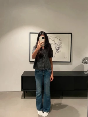 Blå bootcut jeans med fickdetaljer - Säljer ett par klassiska blå jeans med bootcut-modell och snygga fickdetaljer bak. Jeansen har en lätt tvättad look och normal passform, perfekta till sneakers eller boots. Materialet är jeans i bomull och de har låg midja.