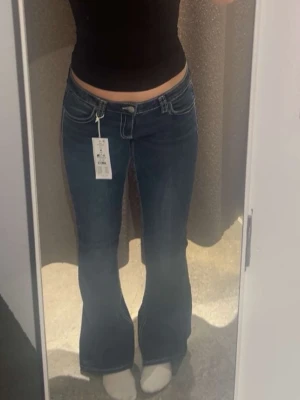 Blå bootcut jeans från Gina Tricot - Säljer ett par mörkblå bootcut jeans från Gina Tricot i storlek M. Jeansen har låg midja, snygga kontrastsömmar och en broderad detalj på bakfickan. Kom gärna med bud!🎀