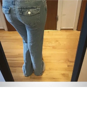 Lågmidjade ljusblå jeans med knappar - Ljusblå jeans med låg midja och lösa ben. Byxorna har knappfickor bak och klassisk femficksdesign. Tillverkade i jeansmaterial och har en avslappnad passform som ger en chill vibe.