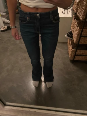 Bootcut jeans från Gina Tricot, blå - Snygga blå bootcut jeans från Gina Tricot i storlek 164. Klassisk femficksmodell med kontrastsömmar och dragkedja. Jeansen har en mörk tvätt och är tillverkade i jeansmaterial med skön passform. Perfekt för dig som gillar en tidlös look. Mellan midja.