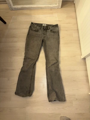 Grå bootcut jeans från 157 - Säljer ett par gråa bootcut jeans från 157 med låg midja. Jeansen har klassisk femficksdesign och är tillverkade i ett mjukt bomullsmaterial med lite stretch. Snygg tvättad look och perfekt passform för dig som gillar retrovibbar.