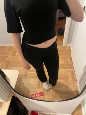 Svart croppad topp med knyt i ryggen - Säljer en svart croppad topp i storlek S med korta ärmar och snygg knytning i ryggen. Toppen har en öppen rygg och är figurnära, perfekt att styla med höga jeans eller kjol. Materialet känns mjukt och stretchigt, vilket gör den bekväm att bära. Finns en likadan i vit.