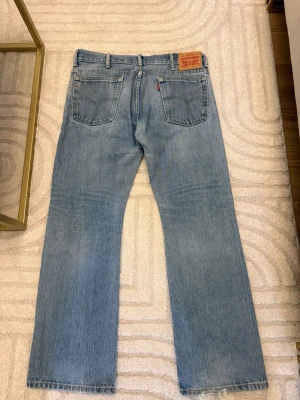 Levi's 501 ljusblå jeans straight fit - Ljusblå klassiska Levi's 501 jeans med rak passform och fem fickor. Jeansen har en ikonisk läderpatch bak i midjan och röd Levi's-tag på bakfickan. Tillverkade i slitstarkt bomullsjeansmaterial med knappgylf och bälteshällor.