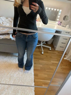 Blå bootcut low waist jeans från Lee - Säljer ett par klassiska blå jeans från Lee med bootcut passform. Jeansen har låg midja, fem fickor och snygga slitningar framtill. Tillverkade i mjukt denimtyg som sitter skönt och ger en avslappnad vibe. Det står storlek W38 i midjemått men jag hade sagt att de är mer S. De är storlek 31 i längden ❤️