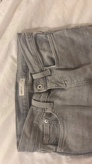 Bootcut grå jeans från Gina Tricot - Säljer ett par helt oanvända gråa jeans från Gina Tricot med design på både fram och bak fickor! Säljer pga att dom aldrig kommit till användning.  Skriv privat för mer bilder!!💓