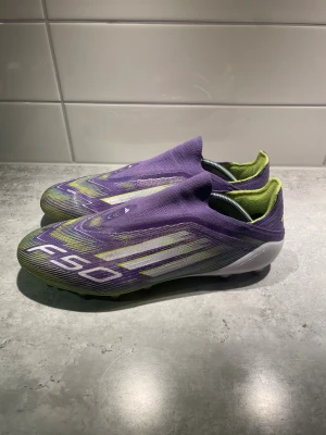 Lila Adidas F50 fotbollsskor - Säljer ett par riktigt snygga Adidas F50 fotbollsskor i lila och limegrönt. Skorna är använda under 5 gånger då de inte passade mig. Har en liten defekt på vänster sko som knappt syns.