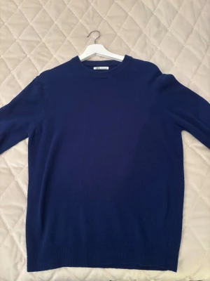 Mörkblå stickad tröja från Zara - Snygg mörkblå stickad tröja från Zara med rund hals och långa ärmar. Perfekt för dig som gillar enkel och stilren design. Tröjan har ribbade muddar vid ärmslut och nederkant, vilket ger en schysst passform. Passar dig som vill ha en klassisk look. Aldrig använd