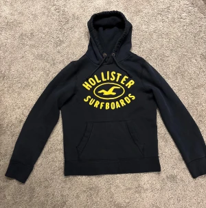 Hollister surf club hoodie - Tja, säljer nu denna väldigt eftertraktade hollister hoodien. Den är är mörkblå och har gul logotyp på hoodien. Den är i storlek M. Tveka inte att höra av dig! Pris kan diskuteras