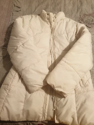 Vit pufferjacka från KappAhl - Säljer en vit pufferjacka från KappAhl i storlek 42-44. Jackan har hög krage, långa ärmar och dragkedja framtill. Quiltad design och två fickor på sidorna. Perfekt för kalla dagar och riktigt mysig att bära.