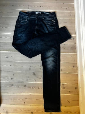 Replay Anbass mörkblå slim jeans - Snygga mörkblå Replay Anbass jeans med slim fit och klassisk femficksdesign. Jeansen har diskreta slitningar och kontrastsömmar som ger en cool look. Materialet är stretchigt jeans och passformen är smal och modern. Perfekta för dig som gillar stilrena och bekväma jeans. Skick 8/10. Nypris: 1799kr