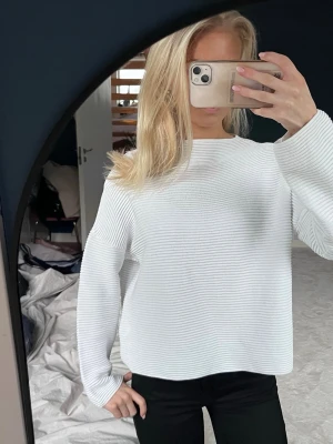 Vit ribbad stickad tröja - Säljer en vit stickad tröja med ribbad struktur och lång ärm. Tröjan har en rak och lite loose passform med rund halsringning. Perfekt att slänga på sig för en clean och enkel look.