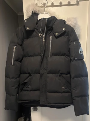 Moose Knuckles jacka - Säljer en svart jacka från Moose Knuckles, den är i storlek M och är i väldigt bra skick har inga flaws eller liknande! Pälsen har hållt sig väldigt bra också och har inge fläckar eller liknande. Hör av er om fler frågor