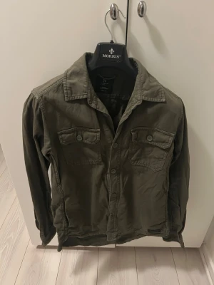 Grön Overshirt - Tja, säljer denna schyssta gröna overshirten som kan användas som lättare jacka eller bara över en hoodie eller tröja. Bra skick och skön att ha. Storleken är S, men kan även passa xs om det skulle behövas. 