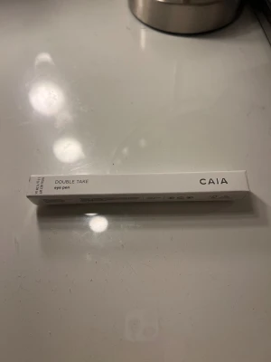 CAIA Double Take Eye Pen - Snygg och praktisk ögonpenna från CAIA i modellen Double Take. Pennan fungerar både som eyeliner och ögonskugga, perfekt för att skapa olika looks. Kommer i en stilren vit förpackning med svart text. Tillverkad i Italien.