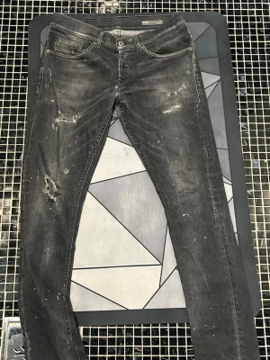 Svarta skinny jeans med slitningar från dondup, stl 32 - Svarta jeans från dondup i storlek 32 med skinny passform. Byxorna har coola slitningar och små vita färgstänk på både fram- och baksidan. Klassisk femficksmodell och knappgylf. Perfekt för dig som gillar stil. Jeansen har slitningar och ett hål vid skrevet, men jätte enkelt att fixa, det är bara att skriva för fler bilder.