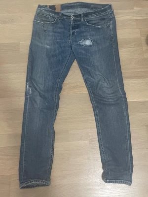 Dondup Jeans - Säljer ett par Dondup i blå färg med snygga slitningar och hål på framsidan. Modellen har smal passform, samt tighta, jeansen är använda samt jag har gått till en skräddare och fixat hålen som längre inte är kvar, vilket bara ger en schysstare detalj.