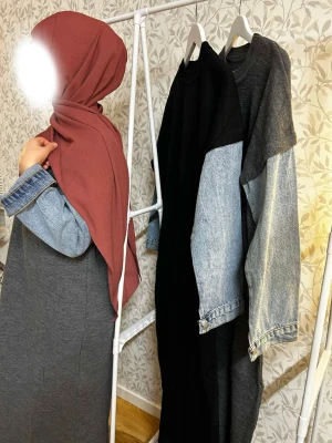 Långklänning med jeansärmar - Cool långklänning i mörkgrått och svart med kontrasterande ljusblå jeansärmar. Klänningen har en loose passform och raka linjer, perfekt för en avslappnad men ändå trendig look. Materialmixen ger en unik vibe och ärmarna har knappdetaljer.